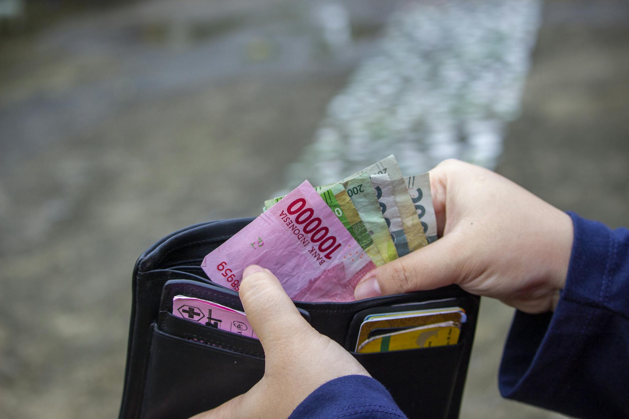 Close-up of hands managing banknotes, focusing on Indonesian Rupiah and diverse currencies